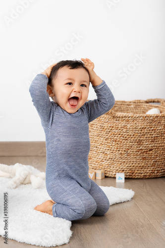 Laughing baby with hands on his head photo