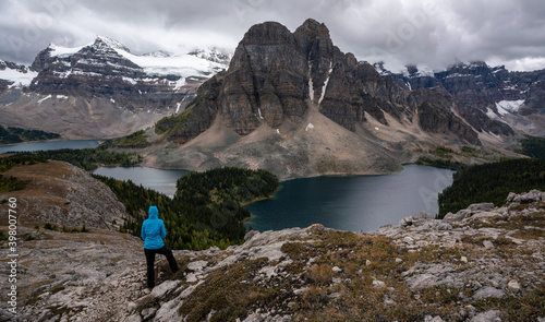 A female hiker standing in front of lakes and high mountains in the backcountry of British Columbia, Canada.