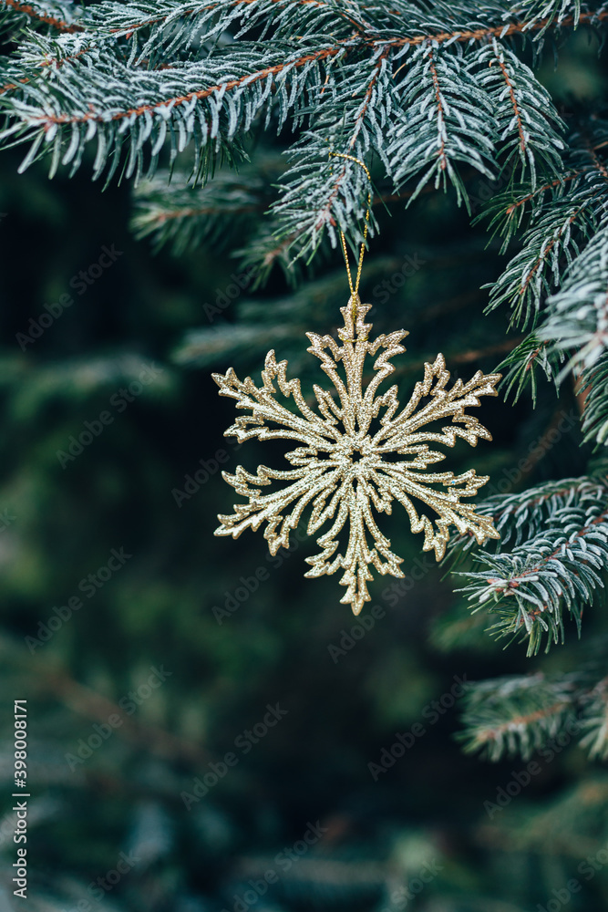 Golden snowflake on a spruce branch with frost. Christmas wallpaper or postcard concept.