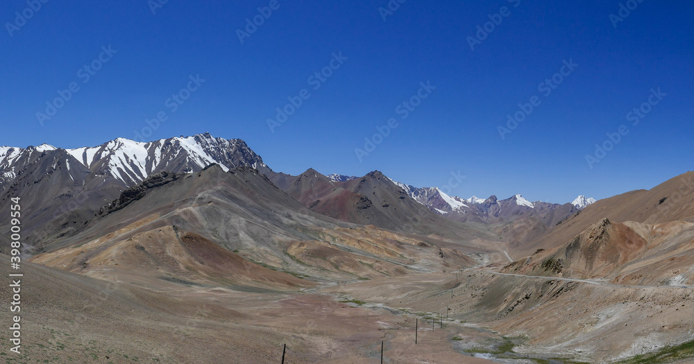Panoramic view with pastel colors of mountains towards the north from high-altitude Pamir Highway at Ak Baital pass in Murghab district, Gorno-Badakshan, Tajikistan