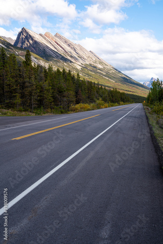 Blue sky with some clouds over a highway with a mountain chain in the background in British Columbia, Canada. © Sebastian