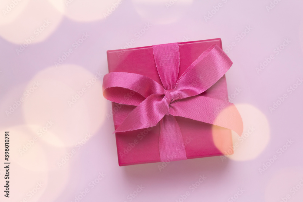 pink gift with christmas lights bokeh in front. pink gift with christmas lights bokeh in front.