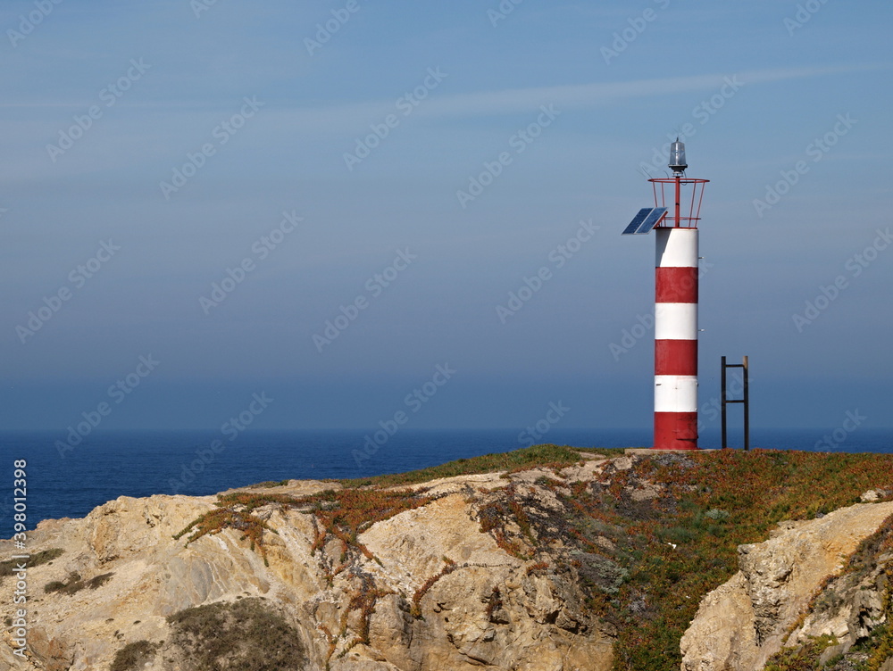 Little red white lighttower on the Alentejo west coast in Portugal 