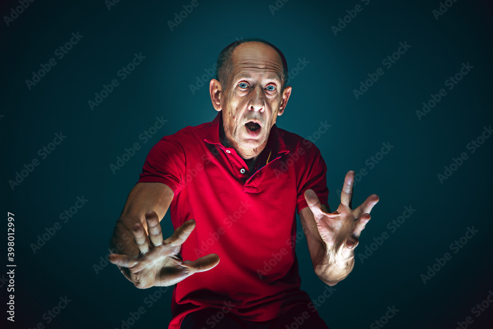 Fototapeta premium Ready to defend. Portrait of crazy scared and shocked caucasian man isolated on dark background. Copyspace for ad. Bright facial expression, human emotions concept. Watching horror on TV, cinema.