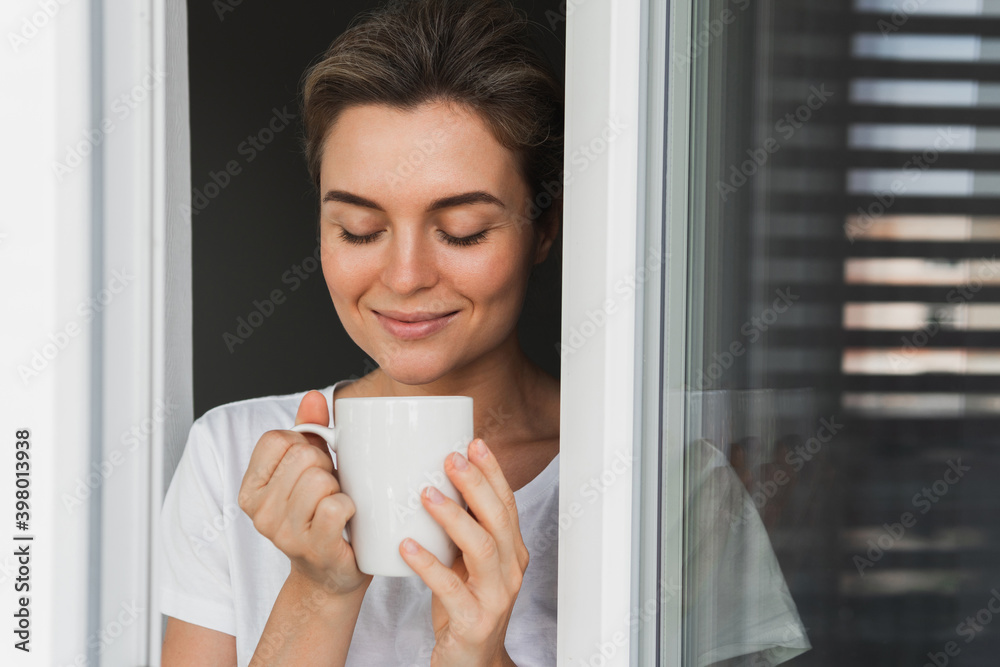 Beautiful woman with a cup of hot coffee looking into the window Beautiful woman with a cup of hot coffee looking into the window