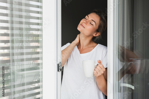 Beautiful woman with a cup of hot coffee looking into the window