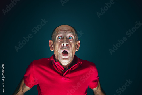 Dumbfounded. Portrait of crazy scared and shocked caucasian man isolated on dark background. Copyspace for ad. Bright facial expression, human emotions concept. Watching horror on TV, cinema.