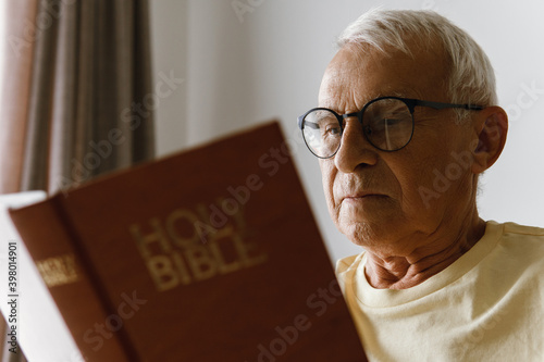 Elderly man reading holy bible photo