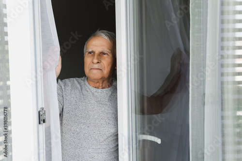 Lonely elderly man looking into the window photo