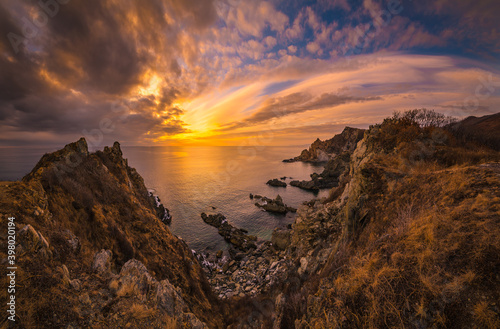 Colorful sunset over the cold winter sea and sharp coastal cliffs