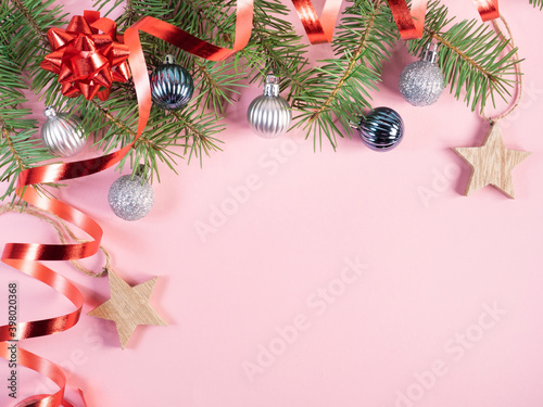 Fir tree branches with christmas decorations on pink 