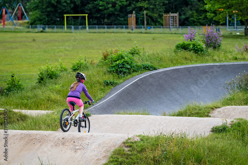 Young girl riding on her bicycle on a dirt race track