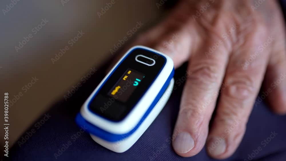 Closeup of digital pulse oximeter on senior person's finger, medical