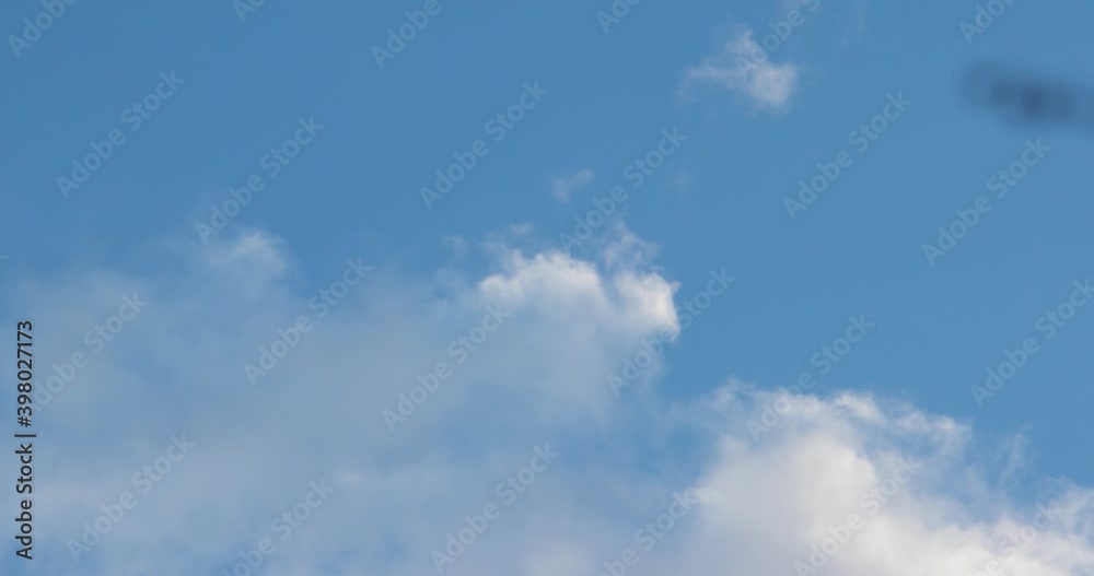 Puffy white clouds passing at fast-forward speed blue sky in the background Puffy white clouds passing at fast-forward speed blue sky in the background