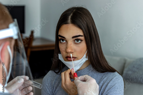 Medic taking sample from patients mouth for coronavirus testing. Photo of Caucasian young woman having a nasal swab test done by her male doctor. Coronavirus test. Medicine, health and virus concept. photo