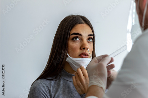 Medic taking sample from patients mouth for coronavirus testing. Photo of Caucasian young woman having a nasal swab test done by her male doctor. Coronavirus test. Medicine, health and virus concept. photo