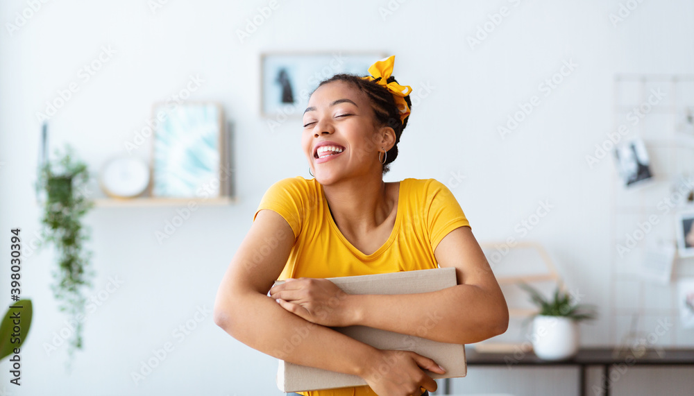 Αυτοκόλλητο Excited black lady hugging and embracing carton box