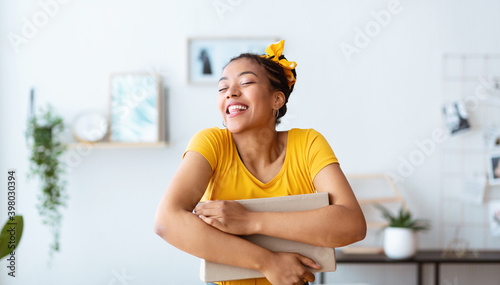 Excited black lady hugging and embracing carton box
