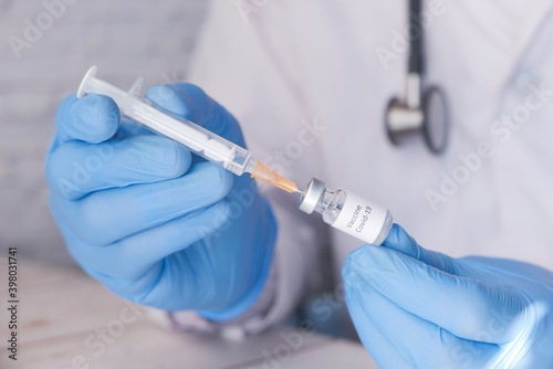 Doctor hands in medical gloves holds syringe and vaccine.