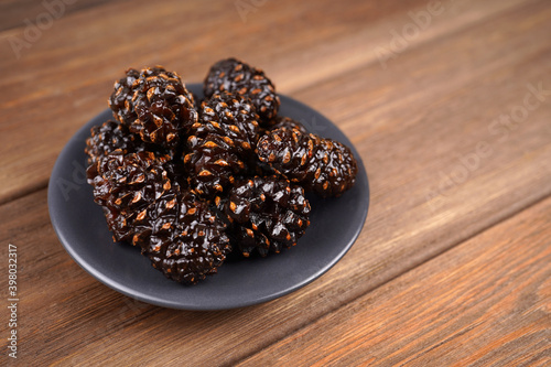 Sweet pine cone candy in black plate on wooden background. Healthy dessert, nutrition, jam recipe concept. Close-up, copy space