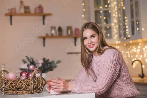 Cute blonde girl in tenderness pink pygamas at christmas decorated kitchen photo