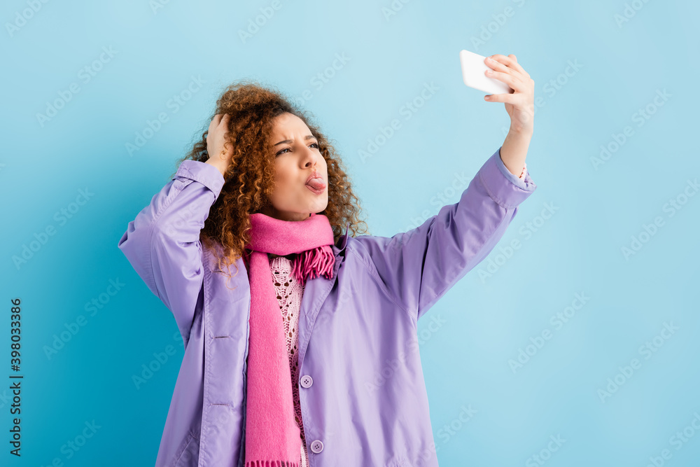 Φωτογραφία Curly young woman in winter coat and pink knitted scarf holding smartphone and s