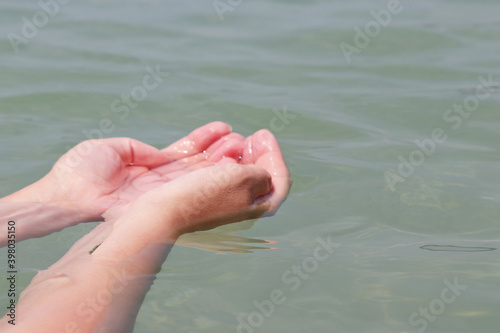 Female hands with folded palms in clear sea water. Concept of ecology, purity and freshness