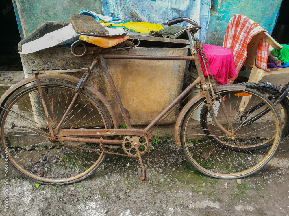 Vintage bicycle covered with rust, parked outside of the house in Indian village
