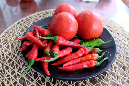Red vegetables on a black plate. Organic tomatoes with peppers on wooden background. Summer or autumn concept. Natural food. It is called 