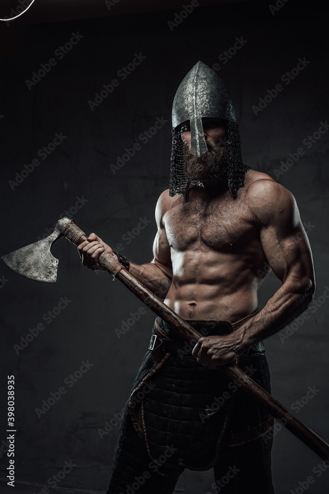 Brutal and muscular northern marauder posing with his two handed axe in dark custom background. Brutal and muscular northern marauder posing with his two handed axe in dark custom background.