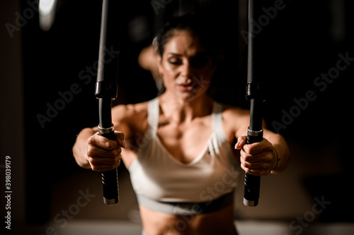 Focus on hands of woman who using machine for pumping group of muscles in gym.