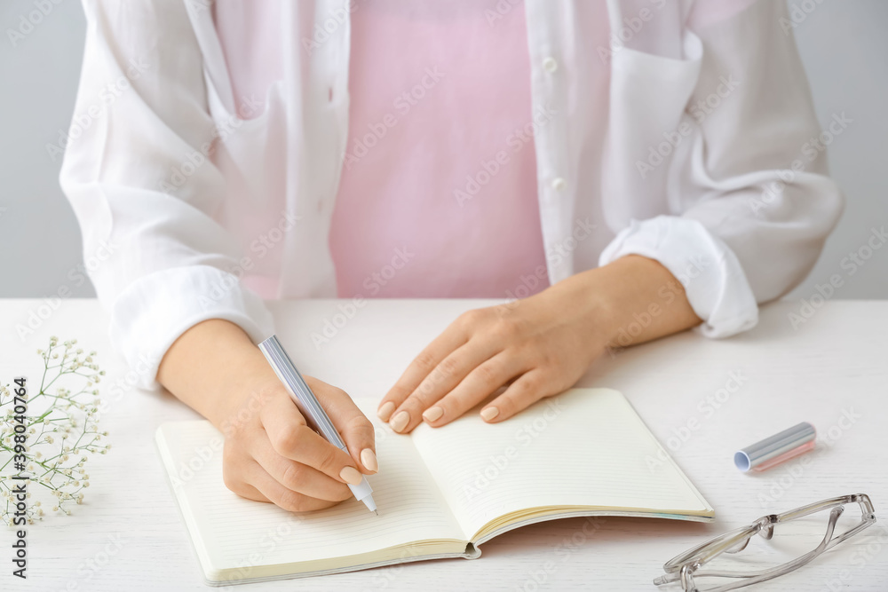 Woman writing in notebook with pen Woman writing in notebook with pen