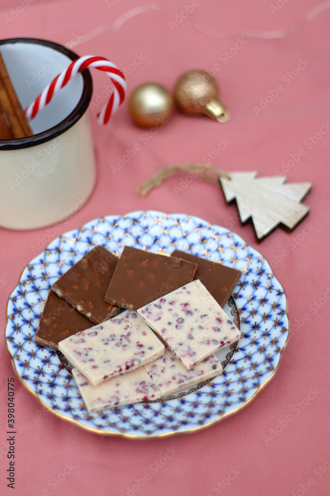 Chocolate pieces, vintage dishes and Christmas decorations. Selective focus, pink background. 