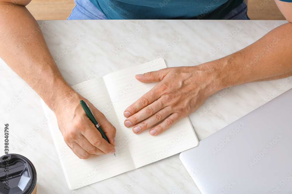 Man writing in notebook with pen