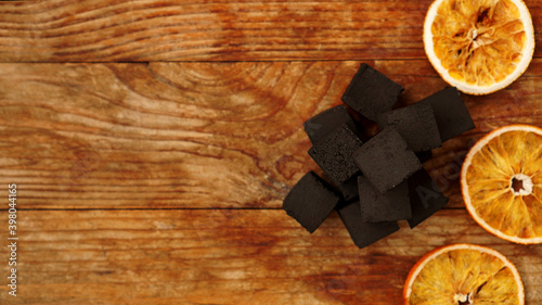 Coals for hookah on wooden background with dry oranges. Place for text and Top view