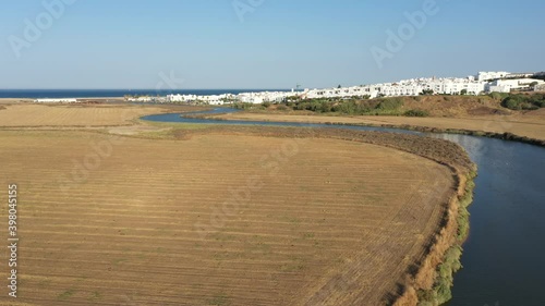 Aerial view of Salado river flowing from the inlad into the Atlantic Ocean passing by Conil de la Frontera in south Spain, Andalusia