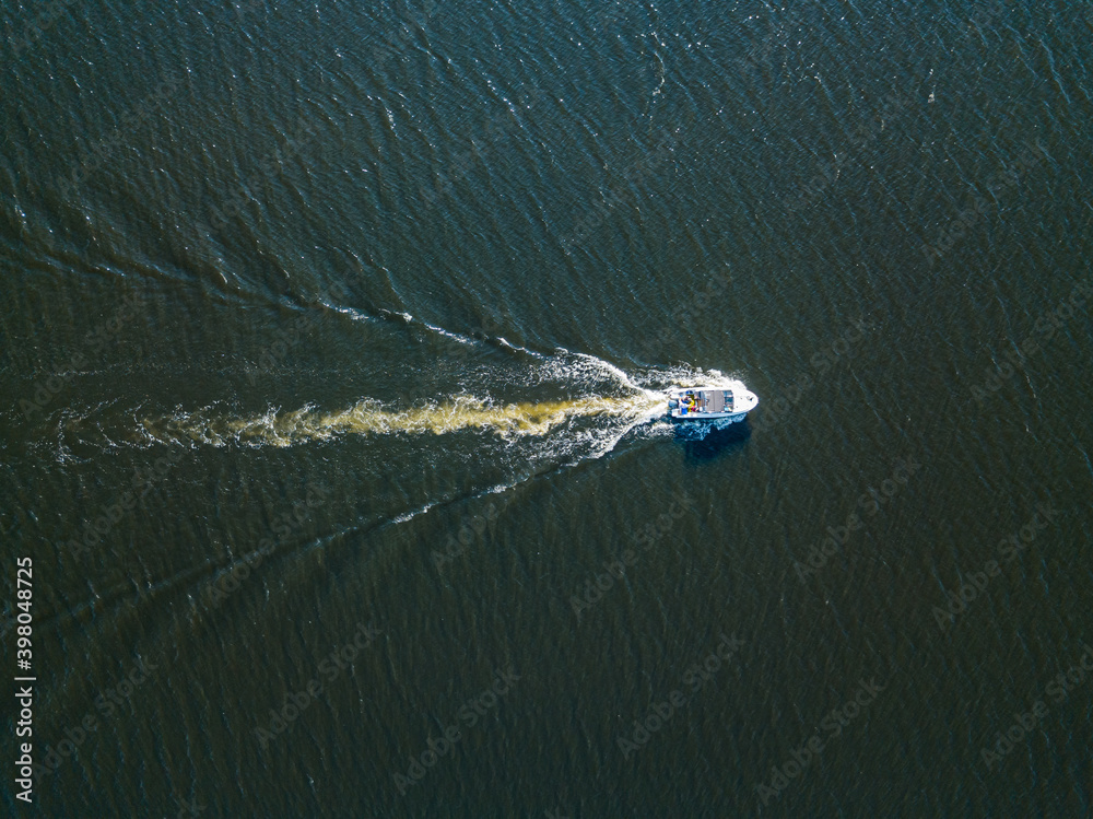 Naklejka premium Aerial drone view. The motor boat is sailing along the river. Sunny summer day, small waves.