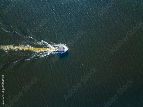 Aerial drone view. The motor boat is sailing along the river. Sunny summer day, small waves.