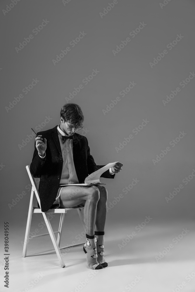 Contract. Young fashionable, stylish man wearing jacket and socks working from home. Fashion during insulation 'cause of coronavirus pandemic. Half business and half home style. Black and white. Contract. Young fashionable, stylish man wearing jacket and socks working from home. Fashion during insulation 'cause of coronavirus pandemic. Half business and half home style. Black and white.