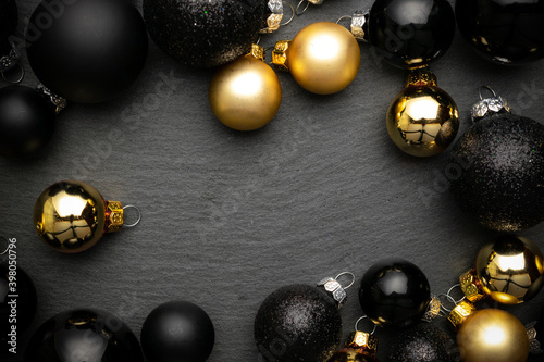 Holiday winter golden. Gold Christmas baubles decoration on black textured background. Decoration and copy space for your text.