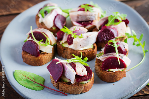 Herring fillet. Sandwich with salted herring and slice beetroot on the  toasts on wooden table. Scandinavian cuisine.