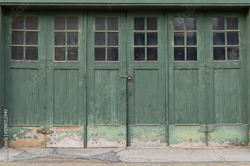 Accordian fold green painted weathered garage doors with windows, creative copy space, horizontal aspect