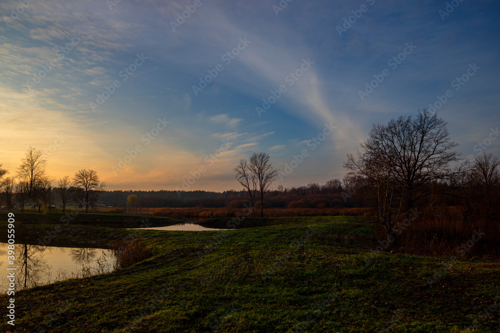 sunset over the meadow with small pond sunset over the meadow with small pond