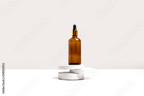 Serum, oil, acid, lotion in brown dropper glass bottle on gray concrete pedestals side view with copy space. Spa products. Organic, bio, natural cosmetic. Beauty, skincare concept. Stock photo