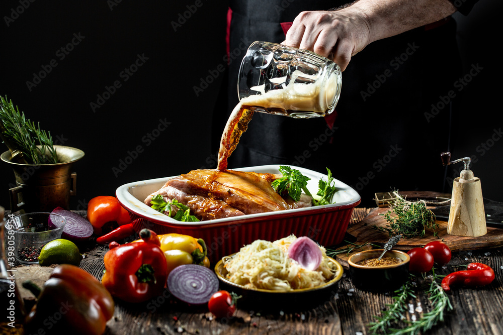 Obraz premium Close up of a chef hands preparing pork knuckle. Cook preparing delicious pork knuckle with the addition of beer. The concept of Bavarian cooking recipe