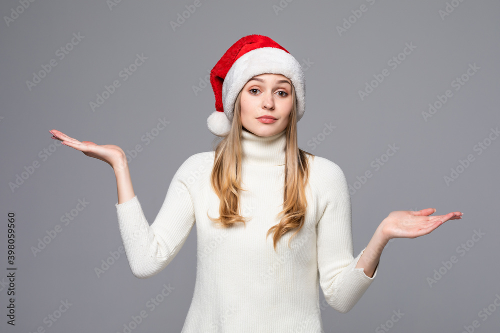 Closeup portrait, unhappy, young, pretty woman in red santa claus hat, asking why, whats the problem, who cares, so what, I dont know isolated gray black background. Negative human emotions Closeup portrait, unhappy, young, pretty woman in red santa claus hat, asking why, whats the problem, who cares, so what, I dont know isolated gray black background. Negative human emotions