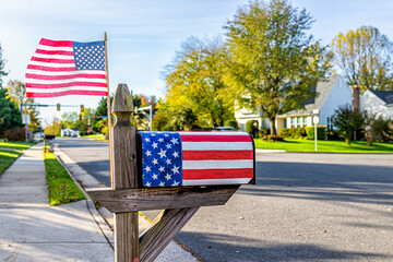 Fairfax County in northern Virginia with patriotic mailbox on election year with stars stripes design and American flag waving in wind by street road in neighborhood