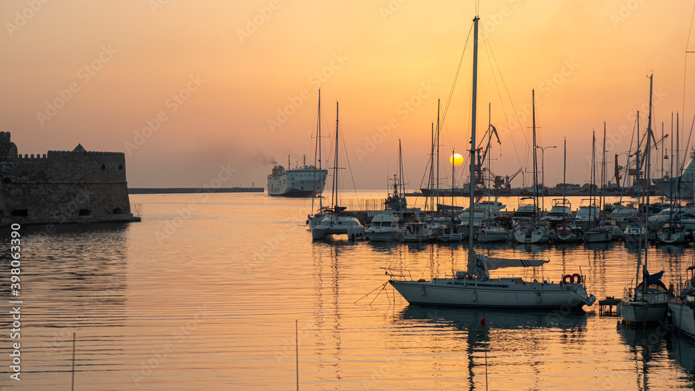 Sunrise at Port. Boats and ship in the port. Sunrise Crete, Greece, Heraklion. Blurred natural color background. Copy space using as background. Landscape on sunrise.