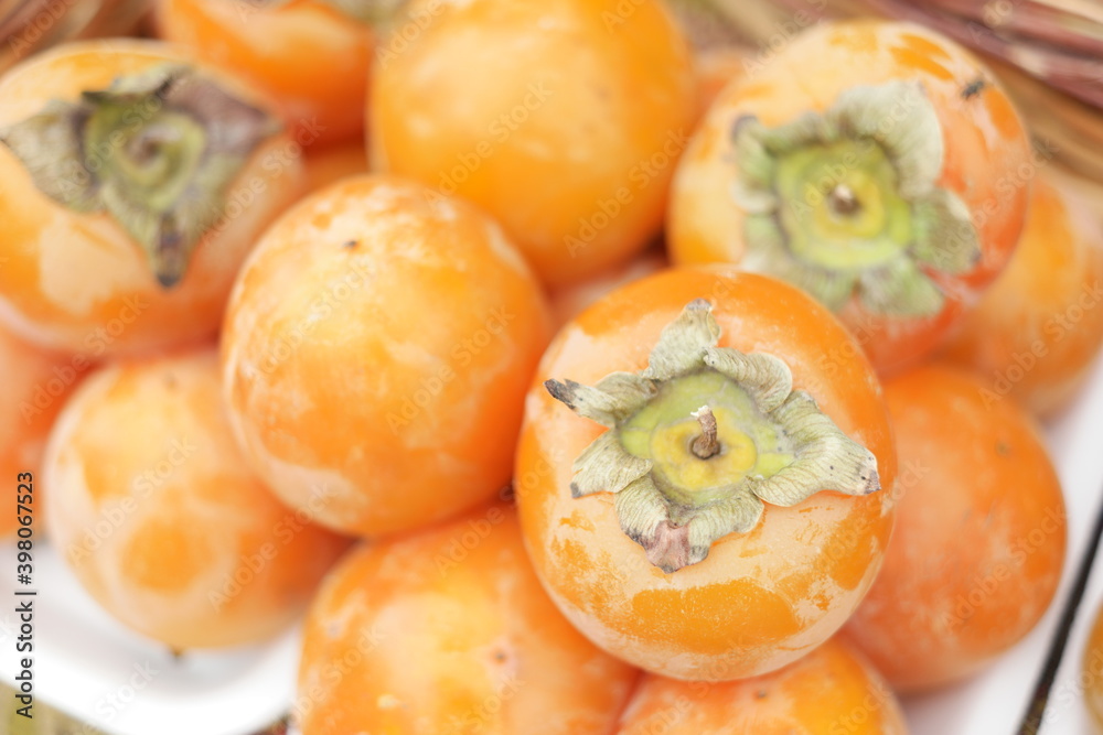 Heap of persimmon fruits close up. Pile of tasty tropical fruits at street market. Rich with vitamins. Heap of persimmon fruits close up. Pile of tasty tropical fruits at street market. Rich with vitamins.