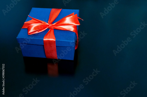 dark blue gift box tied with a red ribbon on a black background